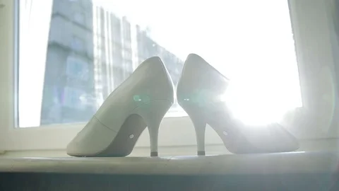Bride wedding shoes stay in the window and sun beams hits them Stock Footage