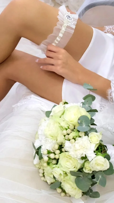 The bride in a white coat puts a garter on her leg. the view from the top. Stock-Footage 305848427