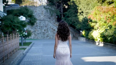 Bride in white dress goes down the avenue Stock Footage 99733277