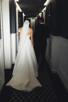 Bride in white gown walks down elegant hallway Foto stock
