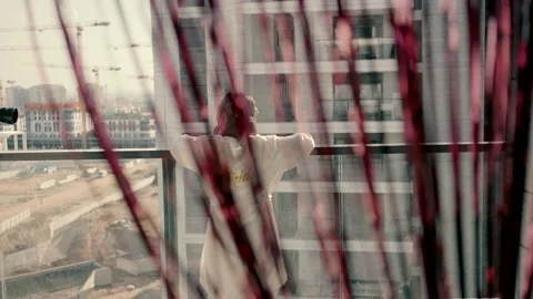 Bride in a white silk robe stands on the balcony Stock Footage 226351410