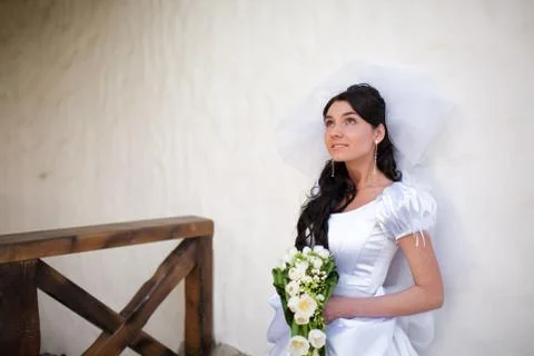 Bride by the white wall looking up Stock Photos