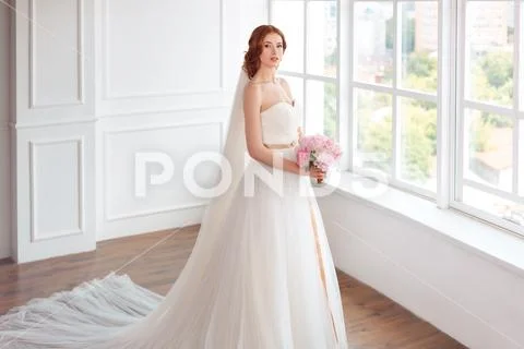 Bride in white wedding dress and long veil with bouquet of flowers Stock Photos