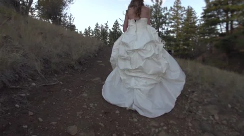 Bride in White Wedding Dress Walking Up Dirt Hill Short in Slow Motion Stock Footage 67904651