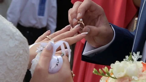 Bridegroom puts on wedding ring to bride's finger Stock Footage 74882577