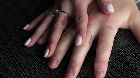 The bride's hand glides gently the arm of the groom. Tattoo is on their fingers Stock Footage 77588681