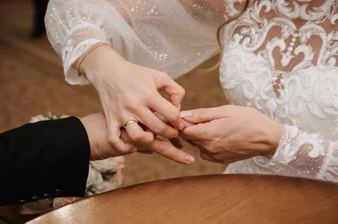 Bride's hand puts a gold ring on the groom's finger on the wedding day Stock Photos