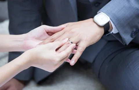 Bride's hand putting a wedding ring on the groom's finger Foto stock