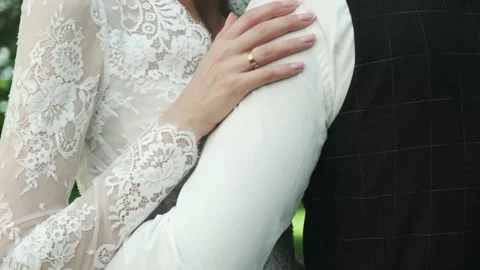 A bride's hand with wedding ring gently stroking the groom's shoulder Stock Footage 317077678
