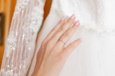 Bride's hand with a wedding ring on a white wedding dress Stock Photos