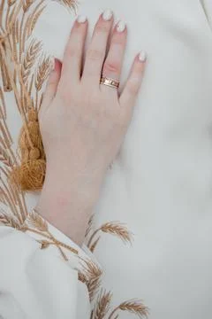 Bride's hand with wedding ring on white embroidered dress 库存照片
