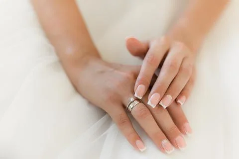 The bride's hands finger adjust the ring on the white dress. Wedding ring close Stock Photos