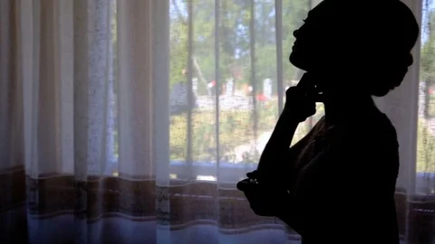 Bride's silhouette in the window that splashes spirits Stock Footage 70390130