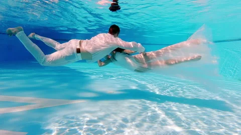 Brides in wedding dresses swim in the pool underwater. beautiful newlywed couple Stock Footage 192868699