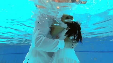 Brides in wedding dresses swim in the pool underwater. beautiful newlywed couple Stock Footage 192875437