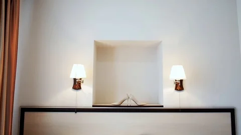 Bride's wedding shoes standing between two wall lights. Video stock 126581323