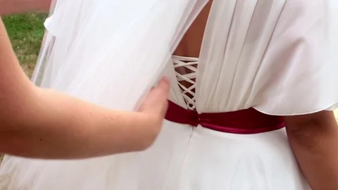 Bridesmaid checking lacing on bride's dress Stock Footage