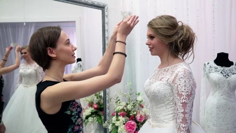 Bridesmaid helped the future bride to choose wedding dress. Young woman Stockbeeldmateriaal 75974591