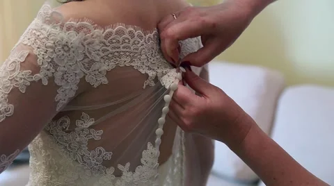 Bridesmaid makes bow-knot on the back of brides wedding dress Stock Footage 65016934