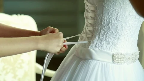 Bridesmaid makes bow-knot on the back of brides wedding dress Stock Footage 70155753
