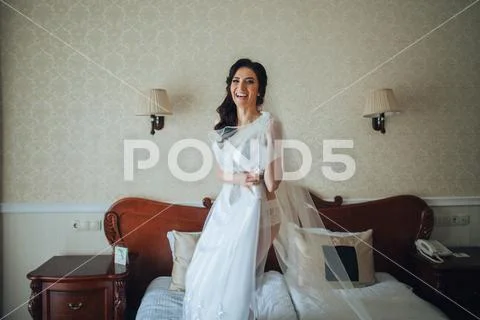 Bridesmaids whirl bride's veil while she smiles Stock Photos