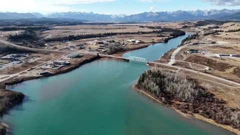 Bridge aerial overlooking Morley Alberta with Canadian Rockies at background Stock Footage 293243177