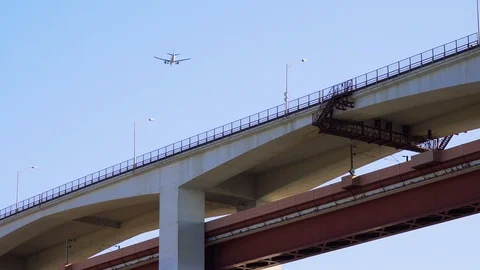 Bridge and flying plane under blue sky Stock Footage 105276340