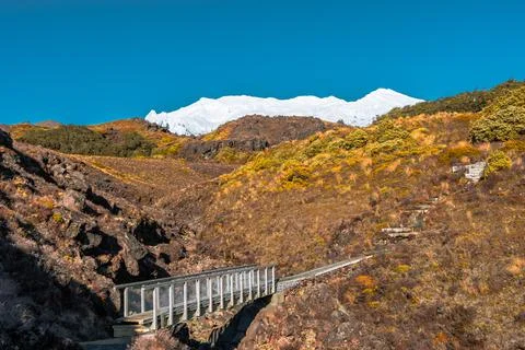 Bridge at bottom of valley, blue sky, spring snow, Mount Ruapehu, New Zealand  Stock Photos