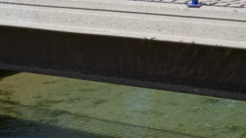 Bridge casting shadow over clear river water outdoors on a sunny day. Stock Footage 308658939