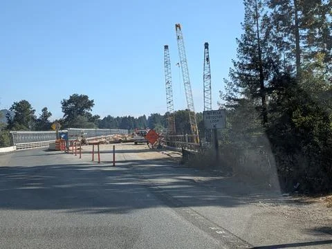 Bridge construction with cranes over river, showcasing infrastructure progress 库存照片