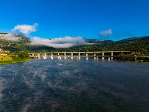 Bridge crosses river under blue sky and clouds in daytime Stock Photos