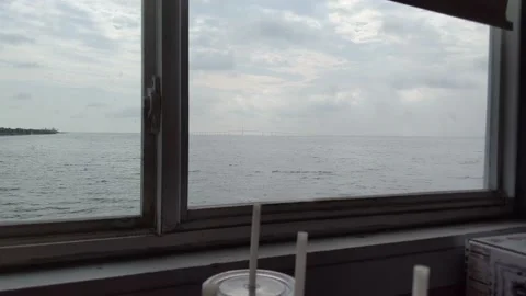 Bridge in distance through window and shoreline with water bottles in foreground 動画素材 158841737