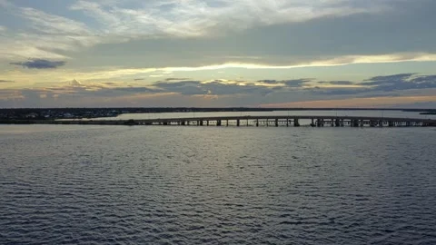 Bridge extending across calm bay waters under dramatic sunset sky Stock Footage 319994754