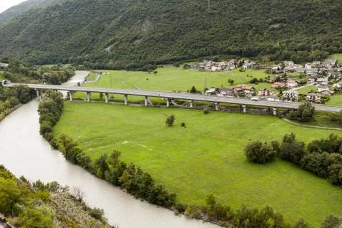 Bridge highway with high pillars over the mountain river entering in the tunnel Stock Photos