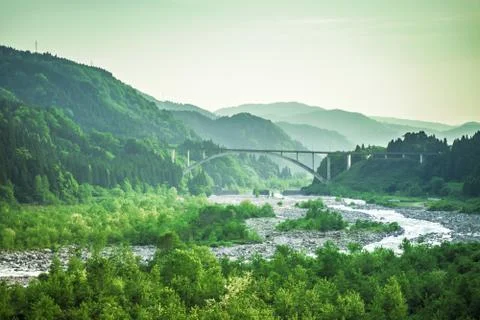 Bridge in the middle of a large forest along a clear river Stock Photos