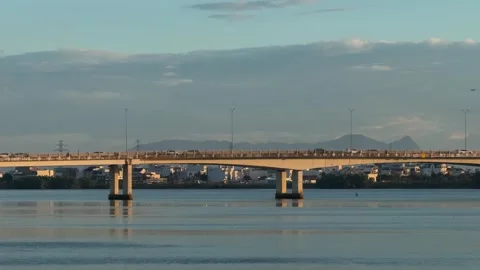 Bridge Over City River with traffic jam at Sunset with Mountain Silhouette in 스톡 동영상 343696272