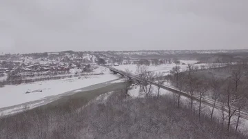 Bridge over a frozen river in winter in a small town Stock Footage 85564907