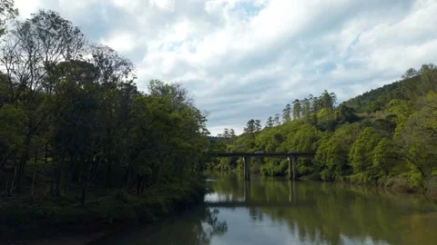 Bridge over green river flowing amid trees and rocks. Irani river. Video stock 317658058