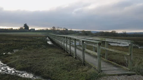 A bridge over a muddy field with a cloudy sky in the background Stock Footage 297958932