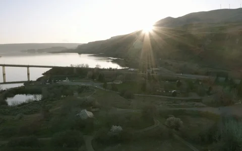 Bridge over Pacific NW River with vehicles crossing &amp; mountains in background 4k Stock Footage 129064981