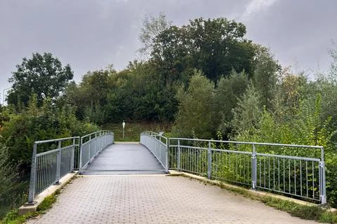 Bridge over a pathway surrounded by trees on a cloudy day Stock Photos
