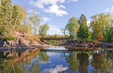 Bridge over a quiet stream in fall Stockfoto's