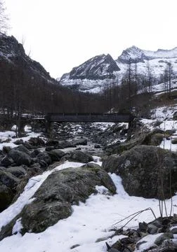 Bridge over the river and snow-covered mountains in the background Stock Photos