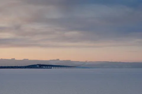 Bridge over a river covered in ice. In the background is the city and the s.. Stock Photos
