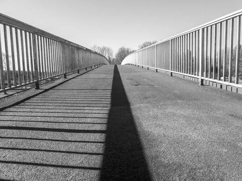 Bridge over a river, with the railing as a shadow in the middle. in black and Stock-Fotos