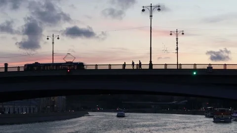Bridge over river. Silhouettes of walking people, moving tram and cars. Stock Footage 136092953