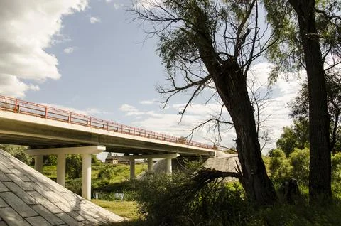 Bridge over the river with trees and blue sky in the background. Stock Photos