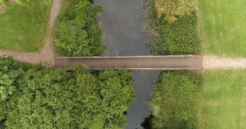 Bridge over small river with green trees and plant life drone aerial 4k Stock Footage 114167648