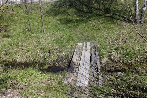 Bridge over a stream with a meadow in the background Stock Photos