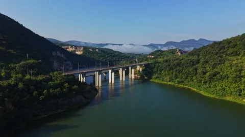 Bridge over water with mountains in background on clear day Stock Footage 340381864